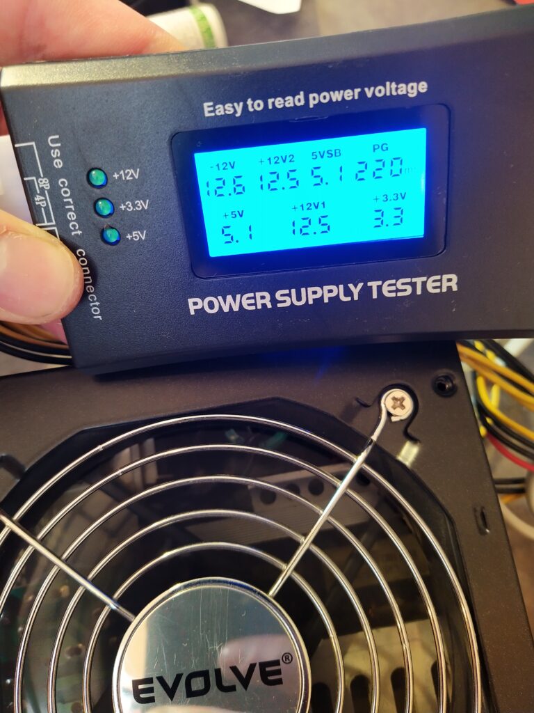 Kontrola napětí zdroje EVOLVE po opravě pomocí testeru počítačových zdrojů.